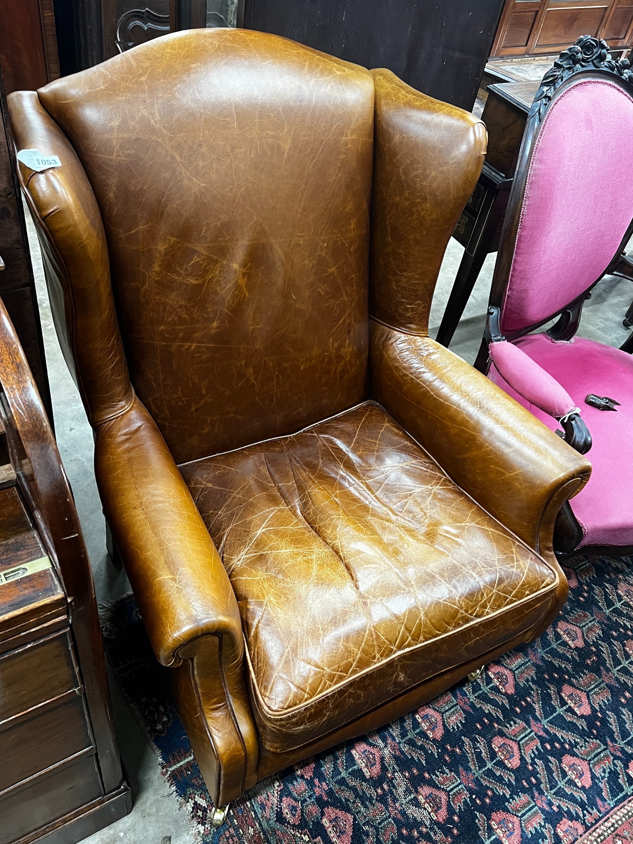 A Victorian style tan leather upholstered wingback armchair, width 78cm, depth 84cm, height 100cm